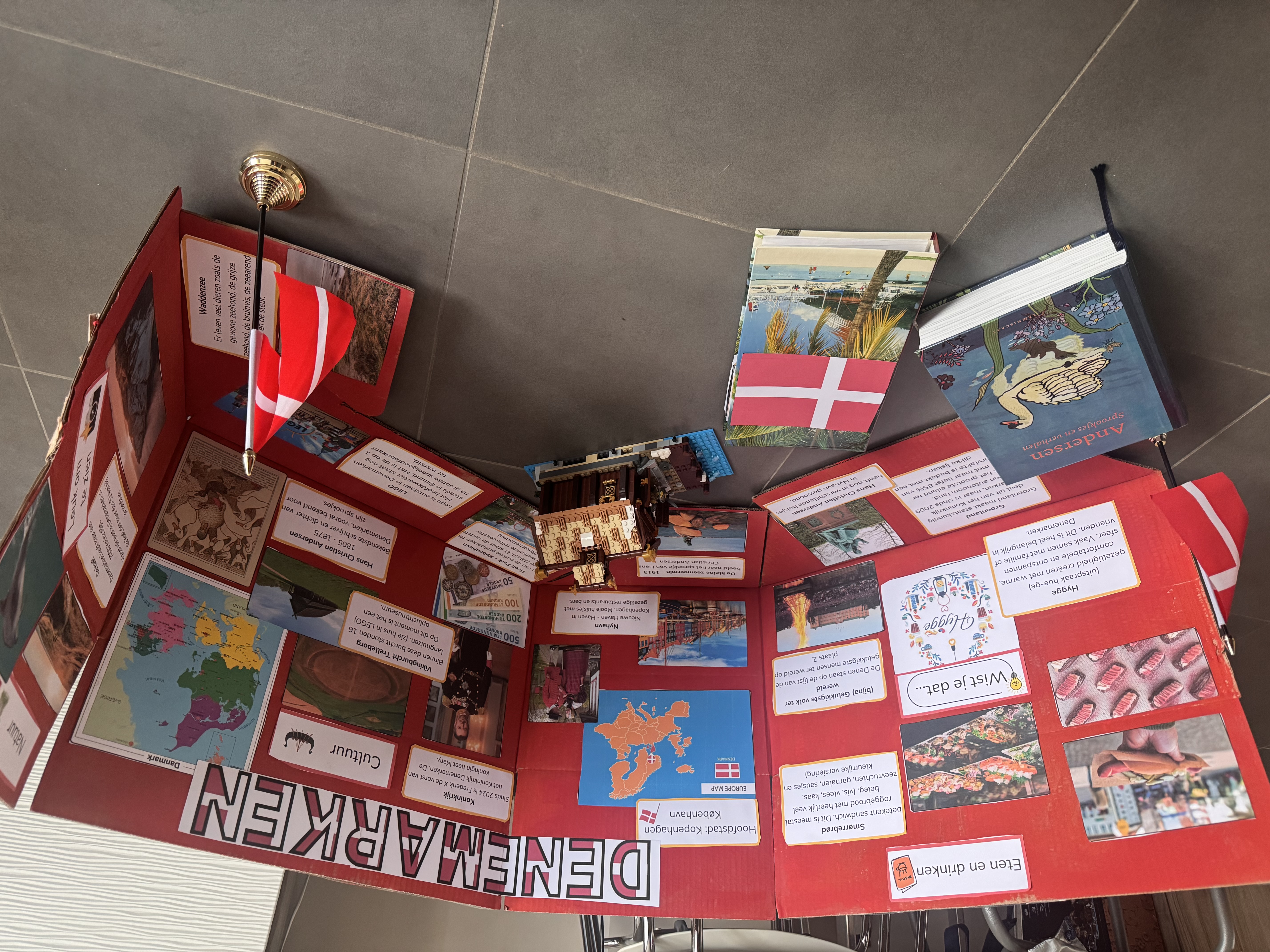 Rode tentoonstellingsstand met foto&rsquo;s, kaarten en boeken over Denemarken, inclusief Deense vlaggen en een LEGO longhouse.
