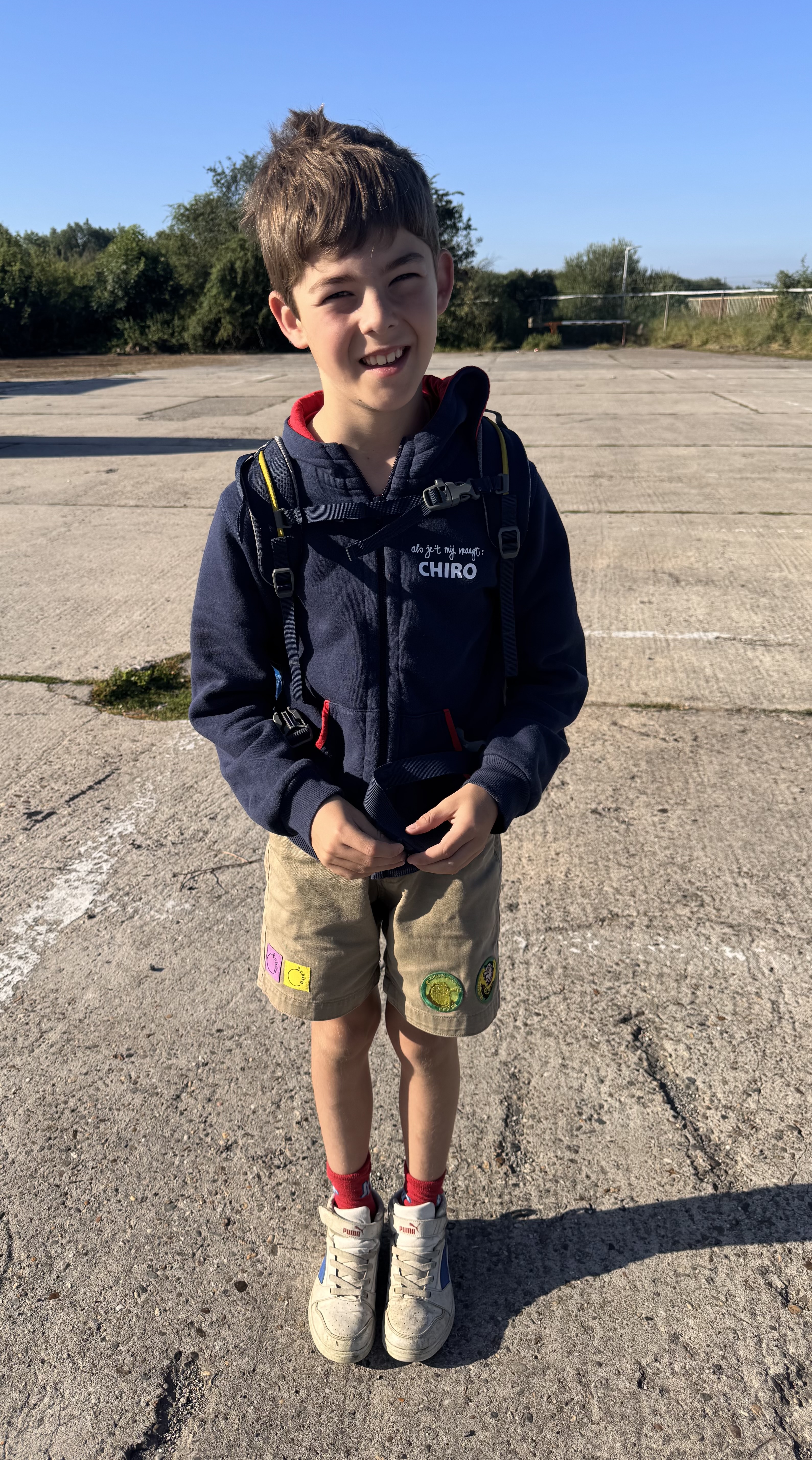 Een lachende Emiel in Chiro tenue staat klaar om te vertrekken op kamp.
